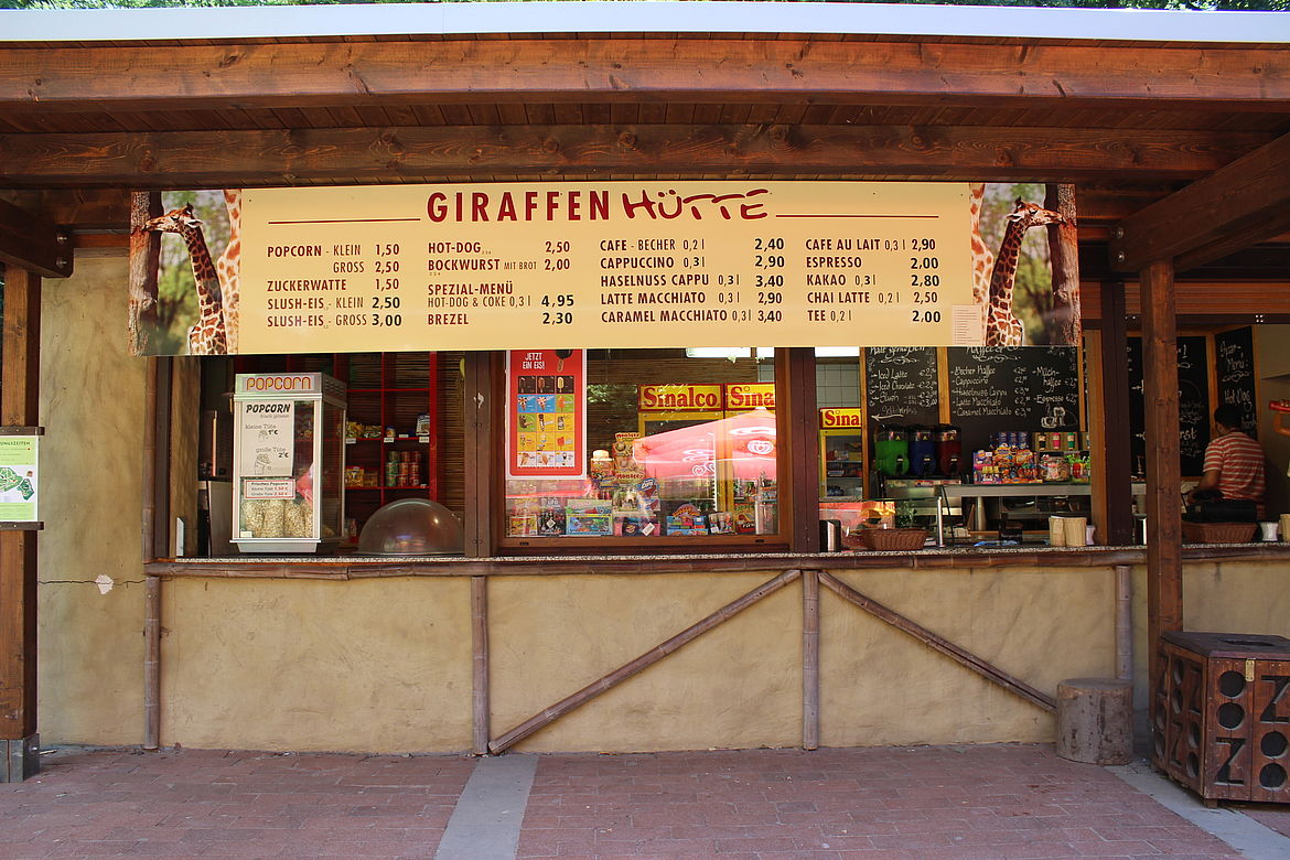 erkaufsstand „Giraffen Hütte“ mit großer Speisekarte, Popcornmaschine und Getränkeausgabe.