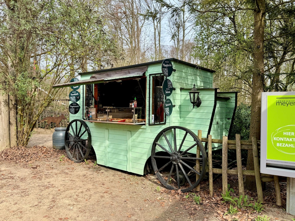 Ein grüner Holzpavillon, der wie ein Wagen gestaltet ist, der als Verkaufswagen für Pizzen dient