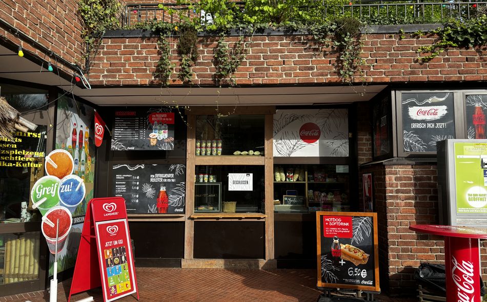 Kiosk mit Verkaufstresen, Getränkewerbung und Schildern.